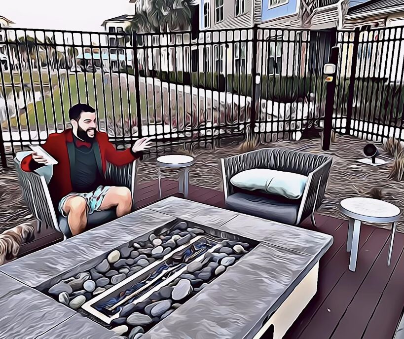 A bearded man in a red tuxedo jacket and teal blue swim trunks sits at an outdoor lanai, leaning forward as if sharing his thoughts with someone just out of frame.